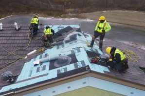 Four workers in reflective vests install solar panels on a suburban house roof.
