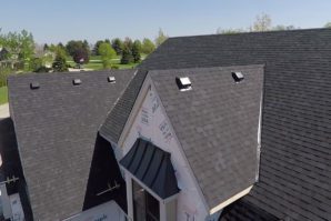 Aerial view of a residential house with a partially completed roof installation, featuring exposed underlayment and several roof vents.