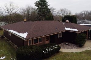 A brown house with snow on the roof.