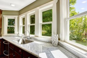 A kitchen with marble counter tops and windows.